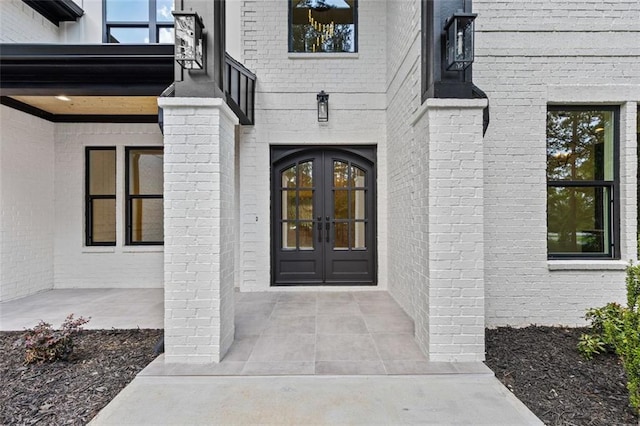 doorway to property featuring brick siding, french doors, and a balcony