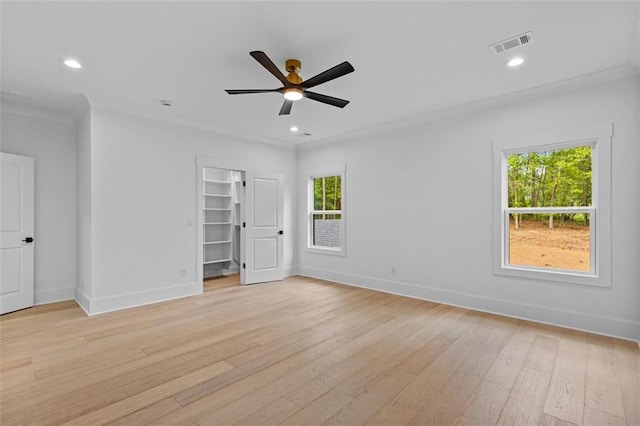 interior space featuring visible vents, crown molding, light wood-type flooring, baseboards, and a spacious closet