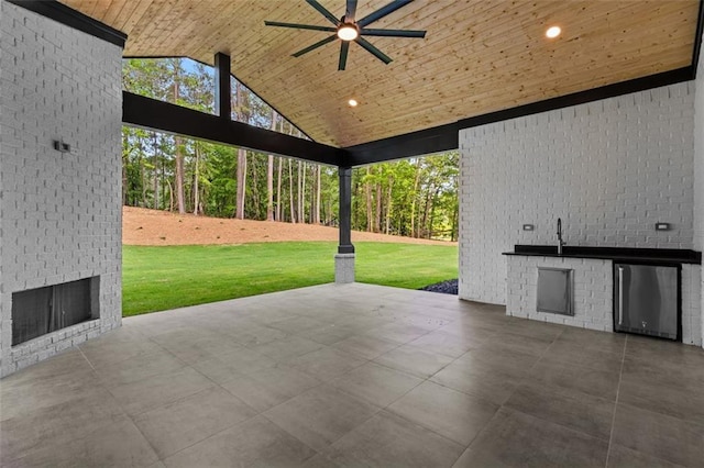 view of patio with exterior kitchen, a ceiling fan, and an outdoor brick fireplace