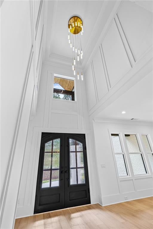entryway with a high ceiling, ornamental molding, french doors, and wood finished floors