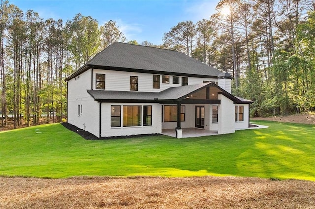 back of property featuring a patio, a lawn, and roof with shingles