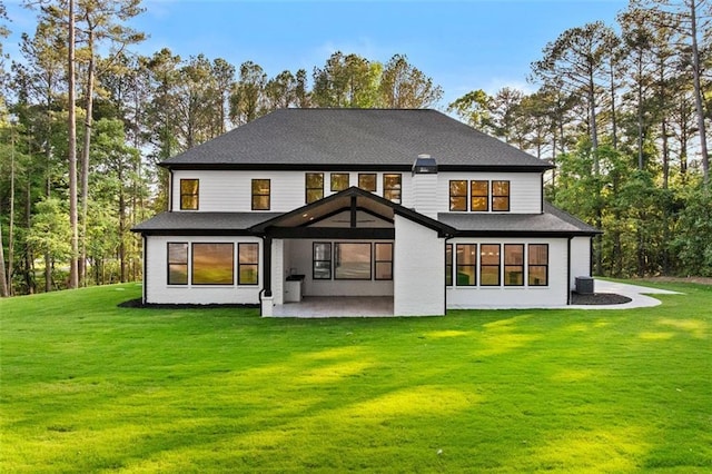 rear view of house with a patio and a lawn