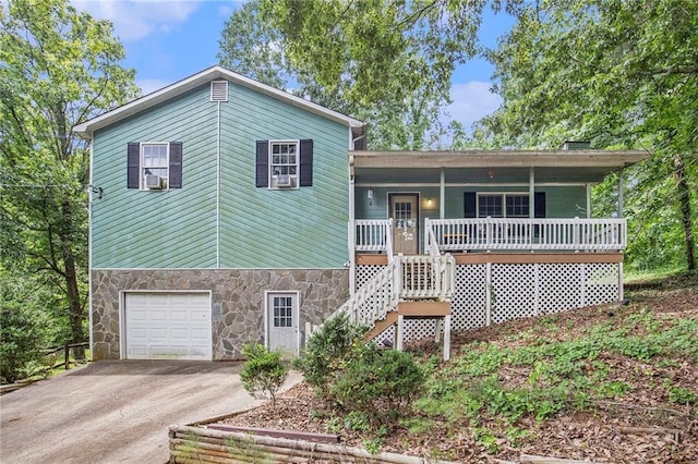 split level home with cooling unit, a porch, and a garage