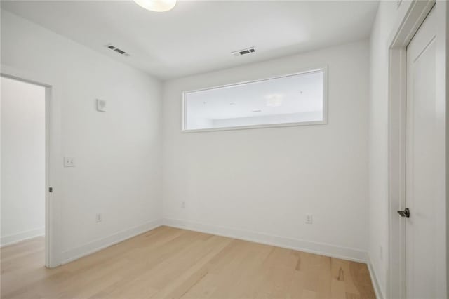 spare room featuring light wood-type flooring, baseboards, and visible vents