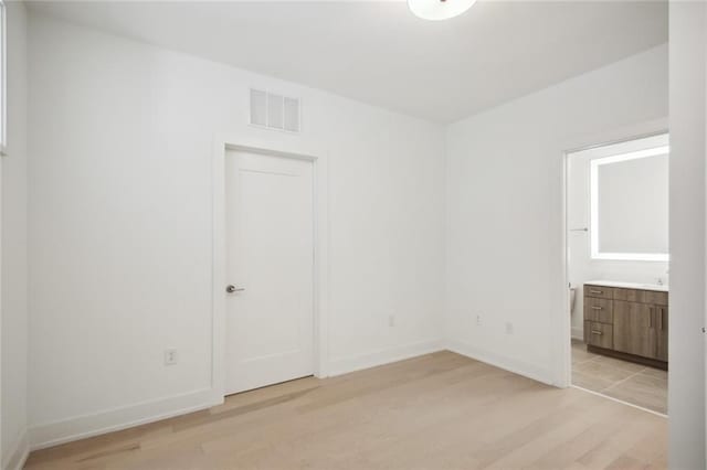 spare room featuring light wood-type flooring, visible vents, and baseboards