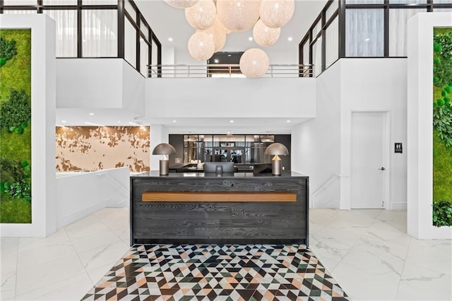 interior space featuring marble finish floor, wainscoting, and a towering ceiling