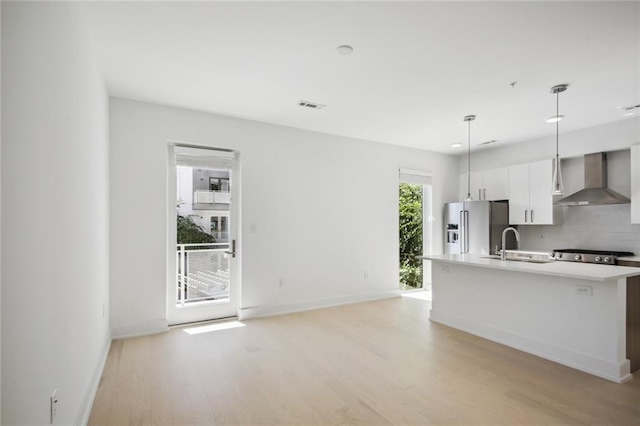 kitchen featuring tasteful backsplash, light countertops, a sink, high quality fridge, and wall chimney exhaust hood