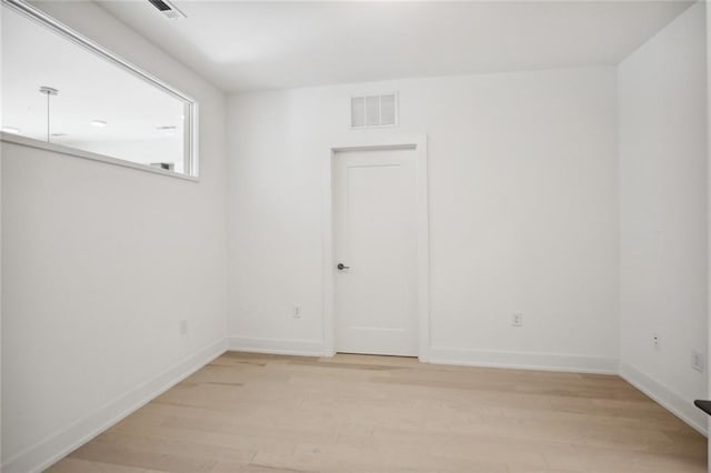 unfurnished room featuring light wood-type flooring, visible vents, and baseboards