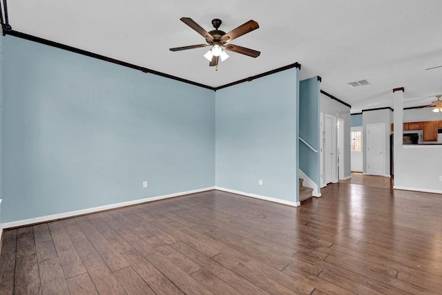 empty room with visible vents, crown molding, stairs, wood finished floors, and ceiling fan