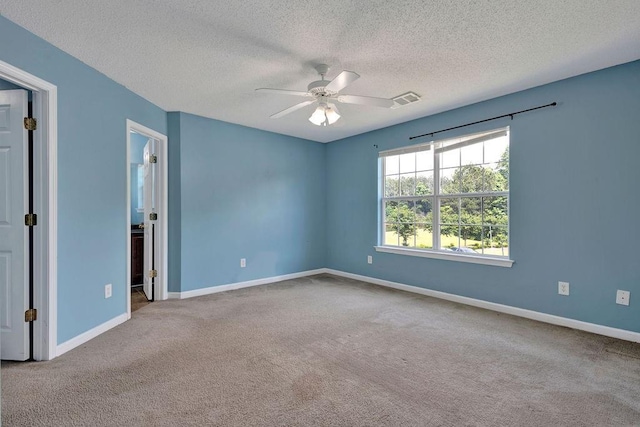 carpeted spare room with baseboards, a ceiling fan, a textured ceiling, and visible vents