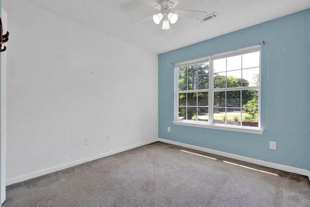 carpeted spare room featuring baseboards, a ceiling fan, a textured ceiling, and visible vents