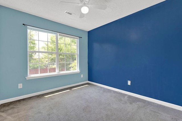 spare room with carpet flooring, ceiling fan, a textured ceiling, baseboards, and visible vents
