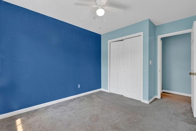 unfurnished bedroom with a closet, carpet flooring, baseboards, and a ceiling fan