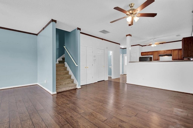 unfurnished living room with crown molding, a ceiling fan, wood finished floors, visible vents, and stairway