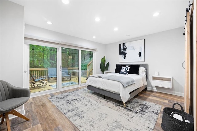 bedroom featuring hardwood / wood-style floors, a barn door, and access to exterior