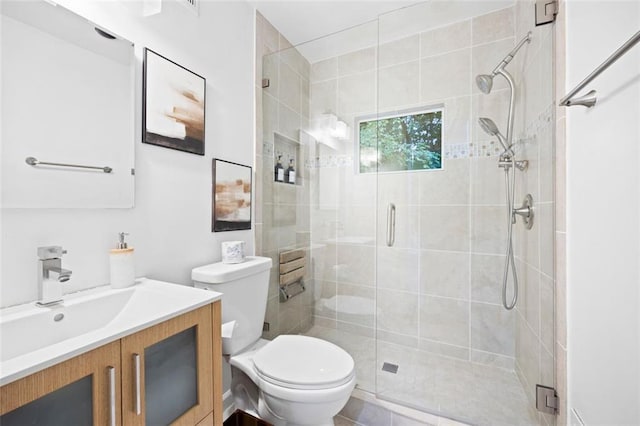 bathroom featuring toilet, a shower with shower door, vanity, and tile patterned floors