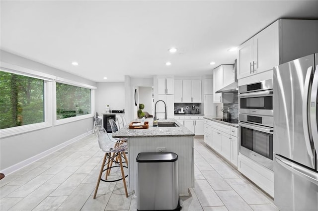 kitchen featuring stainless steel appliances, sink, an island with sink, and white cabinets