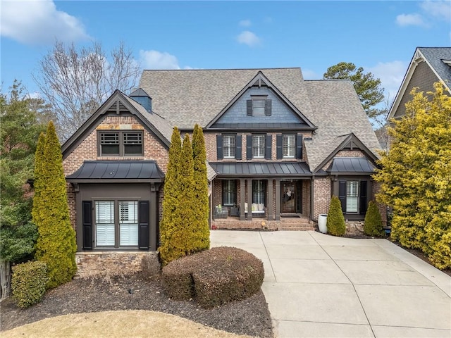 craftsman-style house featuring a standing seam roof, brick siding, a shingled roof, and metal roof