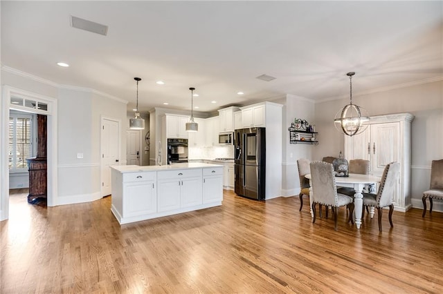 kitchen featuring light wood finished floors, crown molding, light countertops, an inviting chandelier, and black appliances