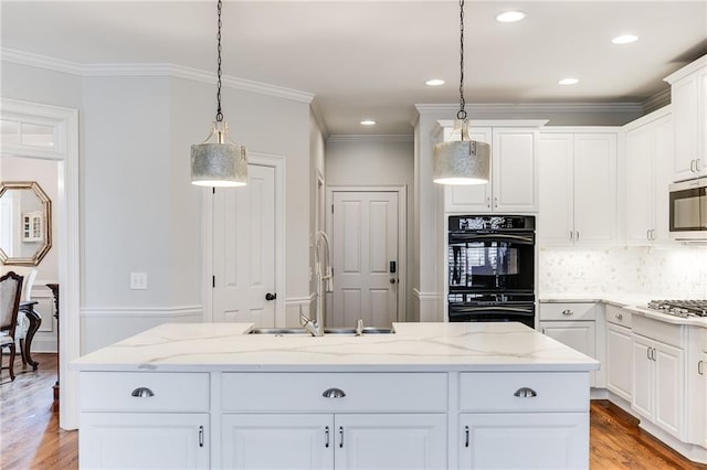 kitchen featuring white cabinets, appliances with stainless steel finishes, light wood-style floors, and a sink