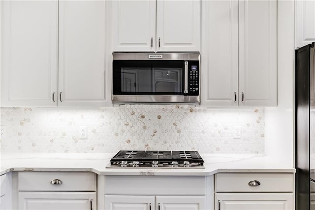 kitchen with white cabinetry, light stone countertops, tasteful backsplash, and appliances with stainless steel finishes