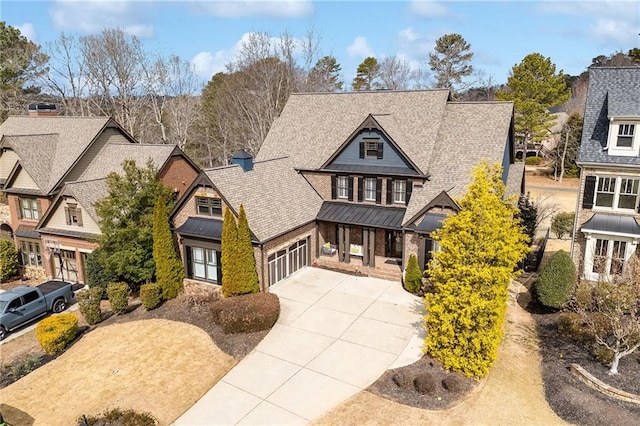 view of front of property featuring a standing seam roof, a residential view, concrete driveway, a shingled roof, and metal roof