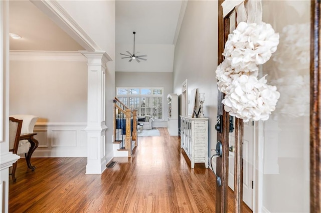 foyer entrance featuring stairway, a ceiling fan, wood finished floors, ornate columns, and a decorative wall