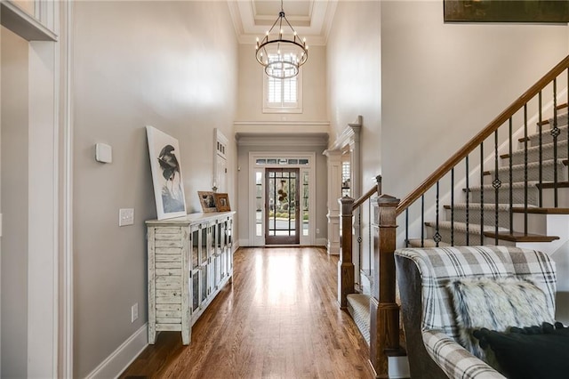 entrance foyer with baseboards, stairway, ornamental molding, an inviting chandelier, and wood finished floors