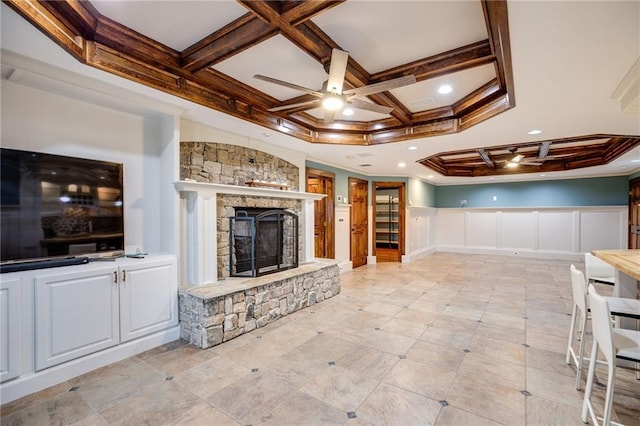 unfurnished living room with beamed ceiling, coffered ceiling, a fireplace, and ceiling fan