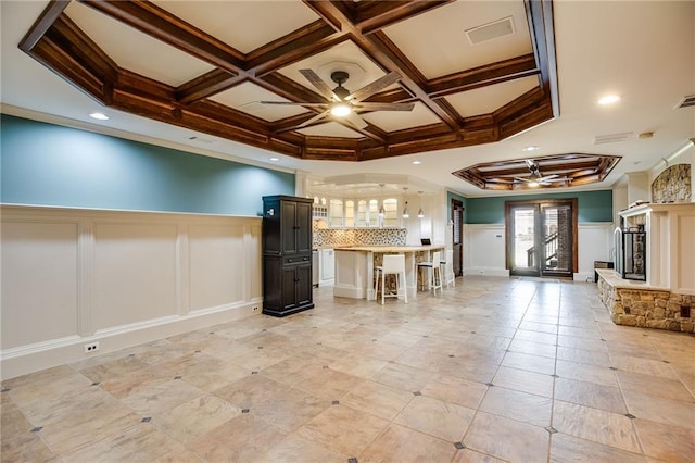 unfurnished living room with visible vents, coffered ceiling, and a ceiling fan