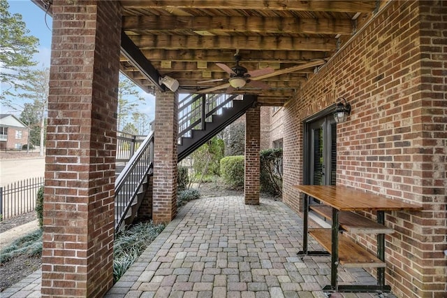 view of patio featuring stairs, fence, and a ceiling fan