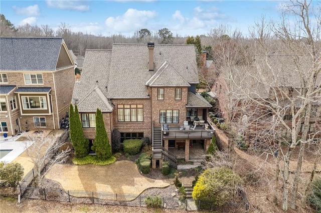 back of property with stairway, roof with shingles, a chimney, a deck, and fence private yard