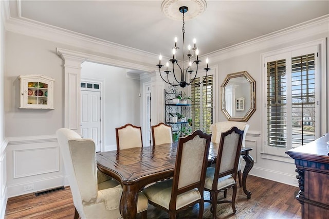 dining area with visible vents, dark wood-type flooring, ornamental molding, and a decorative wall