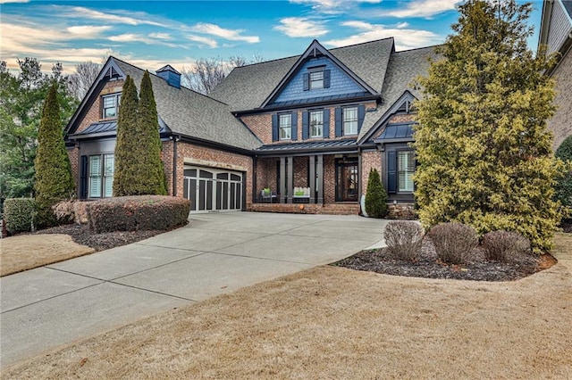 craftsman-style home featuring driveway, a standing seam roof, a shingled roof, a garage, and brick siding