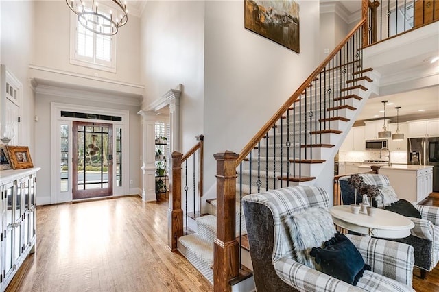 foyer entrance with light wood-type flooring, plenty of natural light, and crown molding