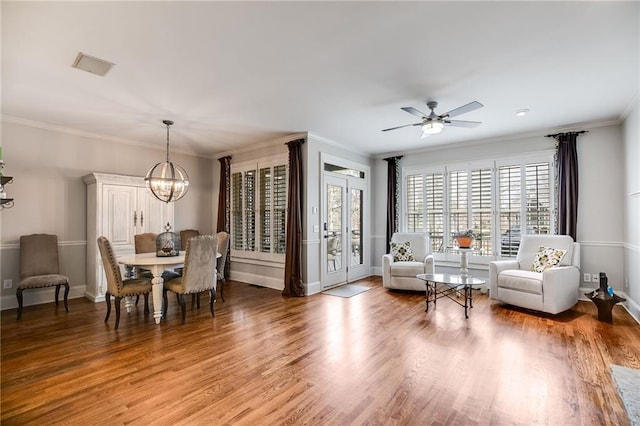 interior space featuring baseboards, wood finished floors, crown molding, and ceiling fan with notable chandelier