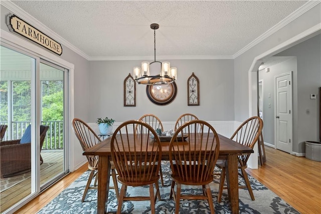 dining room featuring a chandelier, a textured ceiling, light hardwood / wood-style floors, and crown molding