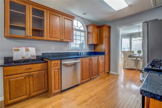 kitchen with sink, light wood-type flooring, a textured ceiling, appliances with stainless steel finishes, and a notable chandelier