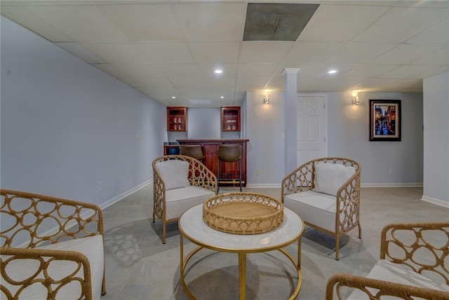 living area featuring indoor bar, light colored carpet, and a paneled ceiling