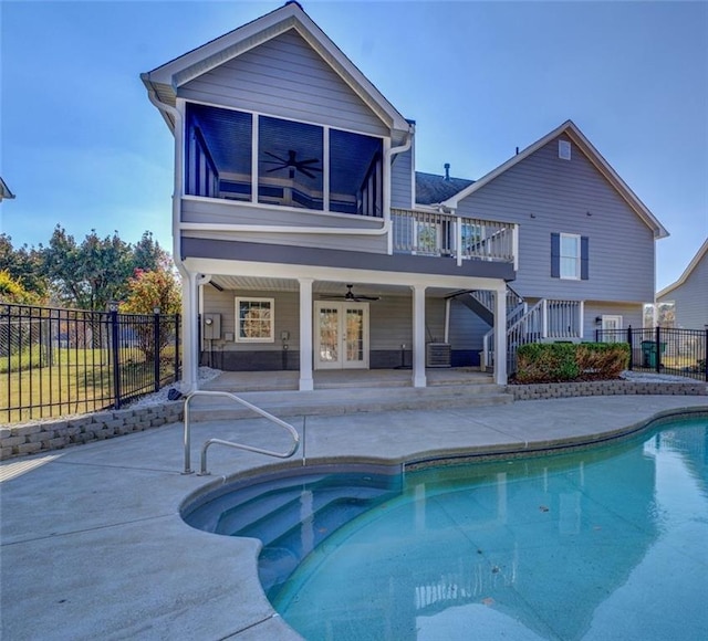 back of property featuring a sunroom, ceiling fan, french doors, a fenced in pool, and a patio area