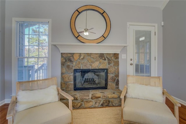 sitting room featuring hardwood / wood-style flooring, a stone fireplace, and ceiling fan