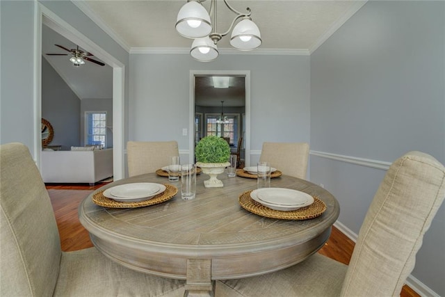 dining room with a wealth of natural light, crown molding, ceiling fan with notable chandelier, and hardwood / wood-style flooring