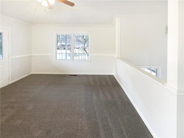 unfurnished room with a ceiling fan, baseboards, dark carpet, and crown molding