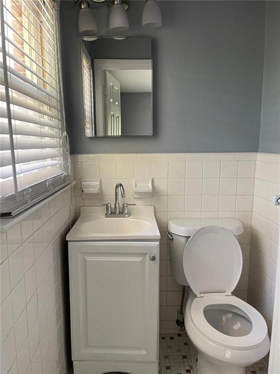 bathroom with vanity, toilet, tile walls, and tile patterned flooring