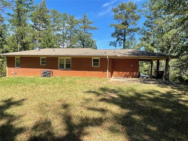 rear view of house with a lawn and a carport