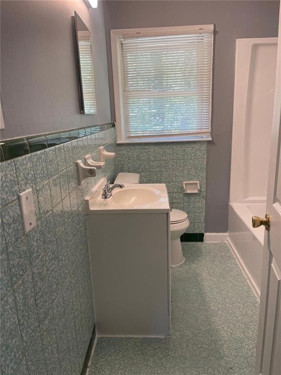 bathroom featuring vanity, toilet, and tile walls