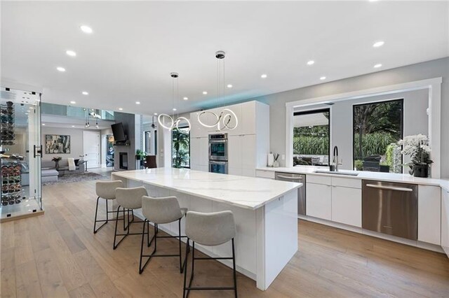 kitchen with pendant lighting, a center island, sink, appliances with stainless steel finishes, and white cabinetry