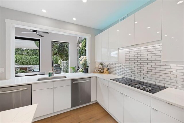 kitchen featuring dishwasher, black electric stovetop, white cabinetry, and sink