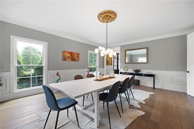 dining space with hardwood / wood-style floors, an inviting chandelier, and crown molding