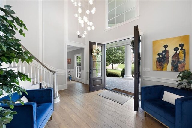 foyer with french doors, an inviting chandelier, crown molding, and wood-type flooring